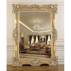 an ornate gold framed mirror with chandelier and sofa in the background on a wooden floor