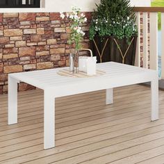 a white coffee table sitting on top of a wooden floor next to a brick wall