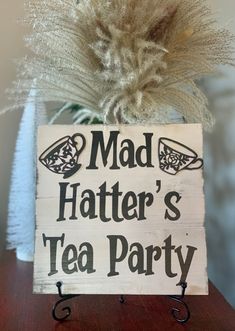 a wooden sign that says mad hatter's tea party on top of a table