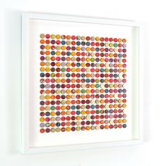 a white framed artwork with multicolored circles on it