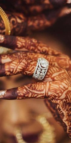 two hands with henna tattoos and rings on them