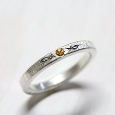 A gorgeous yellowish orange sapphire is flush set into a delicate sterling silver ring. A lovely wedding band with a minimalistic feel. Tiny oxidized engravings on each side of the gemstone mimic little autumn leaves.The sapphire measures between 1.7-2mm. Ring Width: 2.5mm Thickness: 2mmShown in size 6 or 51.5 or 16.5 or L 1/2*Made to order in your size (please allow 3-5 days)nangijalajewelry.etsy.com**Due to the handmade nature of this design you will receive a ring that is a very close copy bu Silver Yellow Sapphire Rings For Wedding, Yellow Sapphire Wedding Ring With Birthstone, Golden Autumn, Sapphire Wedding Band, Hammered Silver Ring, Sapphire Wedding, Orange Sapphire, Put A Ring On It, Thumb Rings