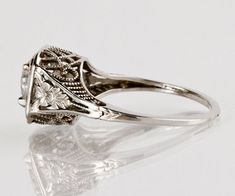 an antique style diamond ring on a reflective surface