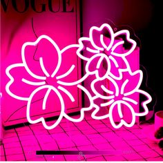 a neon sign with flowers on it in front of a pink wall and tiled floor