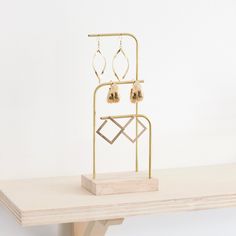 a pair of earrings is on a wooden shelf next to a metal stand with earring hooks