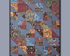 a quilt with many different colors and designs on the front, along with a black frame