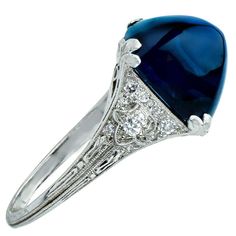 For Sale on 1stdibs - Captivating platinum art deco ring featuring a magnificent A.G.L certified sugarloaf cabochon weighing 11.92 carats from Cambodia with no heat. The band Blue Oval Sapphire Ring In Art Deco Style, Art Deco Blue Oval Sapphire Ring, Elegant Cabochon Sapphire Ring, Blue Cabochon Sapphire Ring In Fine Jewelry Style, Fine Jewelry Blue Cabochon Sapphire Ring, Blue Diamond Cabochon Ring, Blue Cabochon Diamond Ring, Blue Diamond Ring With Cabochon Cut, Formal Cabochon Sapphire Ring