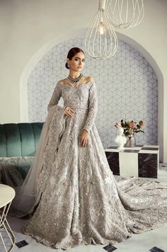 a woman in a long dress standing on a rug with a chandelier hanging from the ceiling