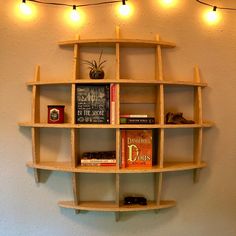 a book shelf with several books on it and lights hanging from the wall behind it