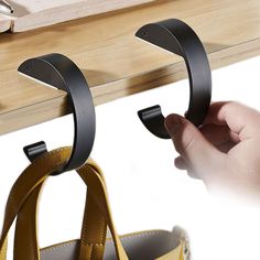 a pair of shoes hanging from hooks on a wooden shelf next to a handbag