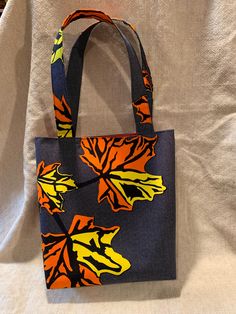 "This versatile tote is the perfect size for shopping, Farmer's Market goods, book bag, or an everyday handbag.  It is hand-sewn of authentic African print fabric with a autumn leaves design.  It is lined and has one inner pocket perfect for keys, cell phone, lip gloss...  The cloth is cotton - cold water wash is recommended.   Approximate measurements: Bag = 12.5\"w X 12\"h Straps = 21\" L Pocket = 5\" X 5.5\" Love these but wish for a different color?.... Requests for custom orders welcome! Thank you for shopping and supporting my small Etsy shop!" Everyday Handbag, Denim Projects, Leaves Autumn, Leaves Design, African Print Fabric, Farmer's Market, Book Bag, African Design, Printed Bags