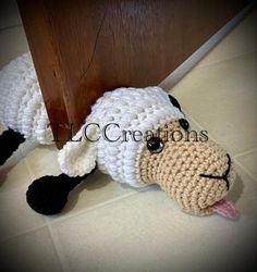 a crocheted sheep laying on the floor next to a door