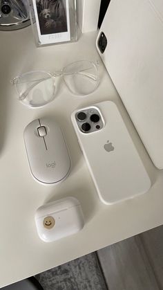 an iphone, mouse, and other electronics are sitting on a white table with glasses