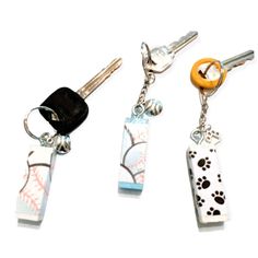 three keychains with different designs on them, one has a dog's paw print