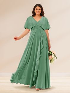 a woman in a long green dress holding a bouquet and posing for the camera with her hands on her hips