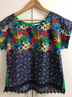 I found this lovely and colourful jungle inspired fabric piece and I envisioned it made into a fun and bright tee. The fabric has been teamed with a contrasting blue/gray light floral and a touch of bright green to create this size 10 boho tee.  This style has a pleat from the back yoke for a relaxed style and sits on or just below the waistline and trimmed at the hem line with matching lace.  The tee could be worn alone or worn over a long sleeved tee with jeans or relaxed pants in the cooler weather. This tee comfortably fits - bust 89-91cm, waist 71-76cm and hips 94-96cm and is priced at $54.95 with free postage in Australia. Blue Patchwork T-shirt For Summer, Colorful Patchwork Short Sleeve Tops, Green Short Sleeve Tops With Plant Print, Green Tops With Plant Print Short Sleeves, Multicolor Patchwork T-shirt For Summer, Casual Short Sleeve Tops With Mixed Print, Cotton Tops With Mixed Print, Fun Green Printed Tops, Vibrant Green Tropical Print Top