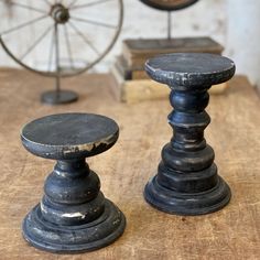 two black candlesticks sitting on top of a wooden table next to a spinning wheel