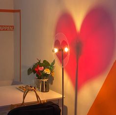 a heart - shaped light shines brightly in the corner of a room next to a purse