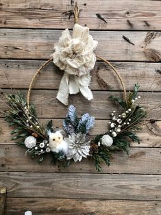 a wreath hanging on the side of a wooden wall with flowers and pineconis