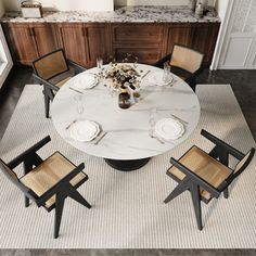 a dining room table with four chairs and a white marble top in front of an island