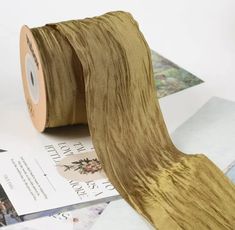 a roll of brown satin ribbon sitting on top of papers