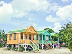 colorful beach huts on the sand with stairs leading up to them