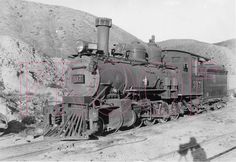 an old black and white photo of a train on the tracks with mountains in the background