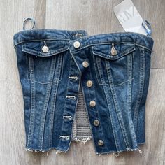 an old pair of jeans with holes and buttons on the bottom are sitting on a wooden floor