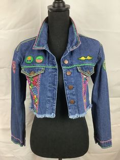 a blue jean jacket with colorful patches on it