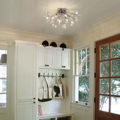 a white coat rack filled with coats next to an open door and window in a room