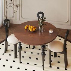 a dining room table with two chairs and a bowl of fruit on top of it