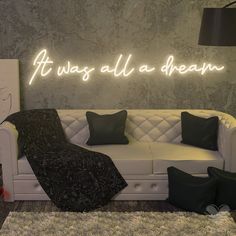 a white couch sitting under a neon sign that says it was all a dream