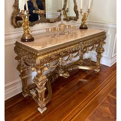 a marble top table with candles and mirrors in front of it on a hard wood floor