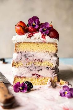 a piece of cake with white frosting and fruit on top is sitting next to a knife