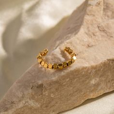 Adorn yourself with this one-of-a-kind 18K gold plated adjustable cube ring, skillfully crafted with golden cube beads in an open design. Perfect for everyday wear, this minimal, geometric, and stylish ring is a rare find! ----------- DESCRIPTIONS ----------- - Size(Length*Width): 2.12cm x 0.23cm- Ring Size: Adjustable- Materials: 18K Gold Plated, Stainless Steel- SKU: JDR363 Gold Cube, Beads Ring, Elegant Gothic, Cube Beads, Crystal Hoop Earrings, Nose Rings Hoop, Stylish Rings, Rings Gold, Fashion Jewelry Earrings