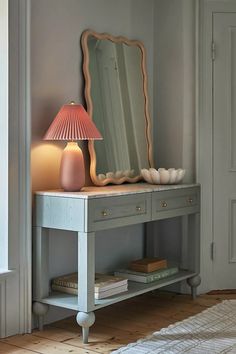 a table with a lamp and a mirror on it in front of a door way