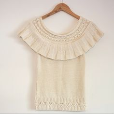 a white sweater hanging on a wooden hanger