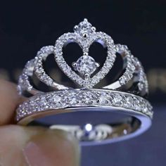 a diamond crown ring is being held by someone's hand