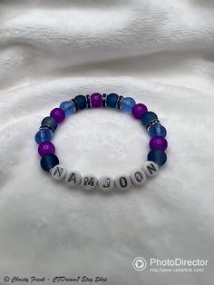 This elastic bead bracelet was made by hand. It was inspired by Namjoon! Happy 10th FESTA! It features glass beads, blue rhinestone spacer beads, & acrylic alphabet beads. 8mm Glass Beads: ~ Blue frosted ~ Purple crackle ~ Blue transparent Please note: ~ I use quality elastic when making the bracelets, but the elastic can still break if overstretched. ~ Sizing Guide: Refer to posted image for more information on 2 sizes available Blue Round Bead Stretch Bracelet For Birthday, Blue Round Beads Stretch Bracelet For Birthday, Blue Round Beaded Stretch Bracelet For Birthday, Blue Letter Beads Stretch Bracelet For Birthday, Blue Beaded Bracelets With Custom Name For Birthday, Blue Round Beads Name Bracelet For Birthday, Custom Name Blue Bracelets With Round Beads, Spiritual Blue Stretch Bracelet With Letter Beads, Elastic Bead Bracelet