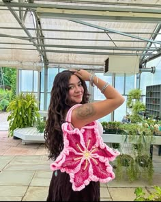 a woman holding a pink crocheted flower purse