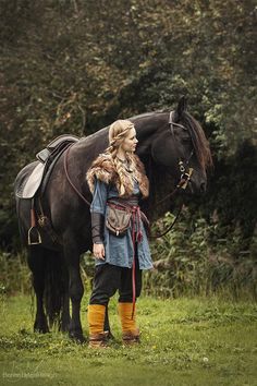 a woman standing next to a black horse