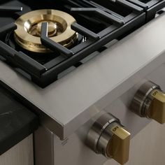 a gas stove with two burners and brass knobs