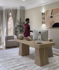 a woman standing in front of a computer on top of a wooden desk next to a couch