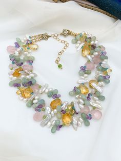 Tanis multistrand statement necklace stands out with beautiful, high quality semiprecious stones including faceted Amethyst, Apatite, Freshwater Pearls, Aquamarine, AAA grade Citrine, AAA grade Rose Quartz, and Peridot. Gold Filled findings and a filigree hook and eye closure top off this showstopper piece perfect for a blushing Bride or beaming Mother of the Bride! Necklace has three strands and is adjustable from 19 inches up to 22.5 inches. ~An enchantingly unique design from Jewelry by Chyri Luxury Multicolor Necklaces With Natural Stones, Luxury Amethyst Multi-stone Necklace, Luxury Multicolor Natural Stone Necklaces, Luxury Multi-stone Amethyst Necklace, Luxury Multicolor Natural Stone Necklace, Luxury Multi-strand Gemstone Beads Jewelry, Elegant Multi-strand Gemstone Necklaces, Elegant Multi-strand Crystal Gemstone Necklaces, Elegant Multi-strand Crystal Gemstone Necklace