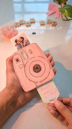 a person holding up a pink camera with photos on the front and back of it