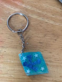 a blue square shaped keychain sitting on top of a wooden table