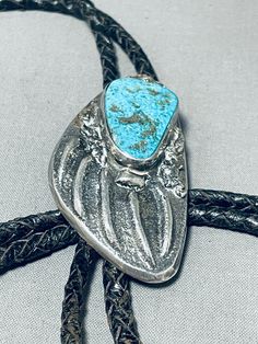 MAKE US AN OFFER BY CLICKING THE "MESSAGE SELLER" Button- A tremendous vintage Navajo silver bolo.   Here we have a sand cast bolo with a cool paw design that hosts a large, impressive Pilot Mountain turquoise stone!  It has a black leather braided tie with 2-?" silver tips and is about 42" in length! The center stone measures around 1-1/8" x 3/4". Sterling silver. The bolo measures around 2-1/2" x 1-3/8". Sturdy 64 grams.  Make Us an Offer- Due to the high demand of our items, many pieces sell Vintage Navajo Jewelry Leather, Vintage Turquoise Bolo Ties For Rodeo, Vintage Turquoise Bolo Tie For Rodeo, Handmade Turquoise Vintage Bolo Ties, Handmade Vintage Turquoise Bolo Ties, Vintage Blue Turquoise Necklace With Concho, Vintage Turquoise Necklace With Concho Detail, Pilot Mountain, Silver Tips