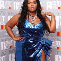 a woman in a blue dress poses for the camera on the red carpet at the brit awards