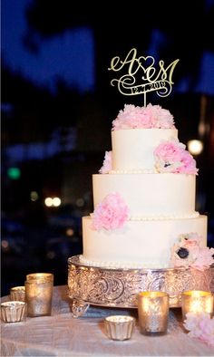 a white wedding cake with pink flowers and candles