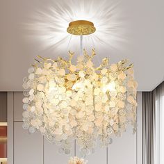 a chandelier hanging from the ceiling in a living room with white walls and flooring